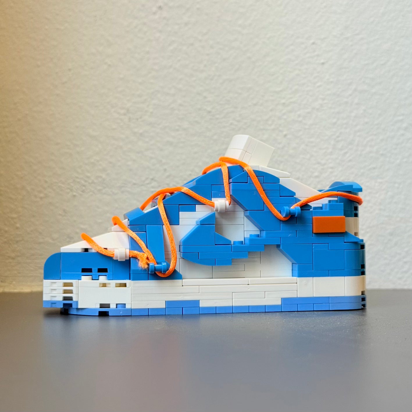 Build your Grail. De unieke bouwset om jouw favoriete sneaker in Lego blokjes na te bouwen. Wordt geleverd met instructieboekje (via QR-code), bouwsteentjes en een klein zwart schoenendoosje. Dit is de variant: Nike Dunk Low UNC x Off White x Futura.